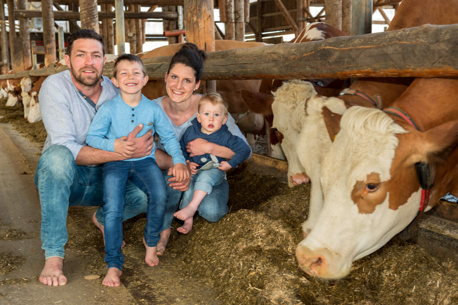 Stefan & Verena Enzenhofer mit den Kindern in ihrem Stall bei den Tieren